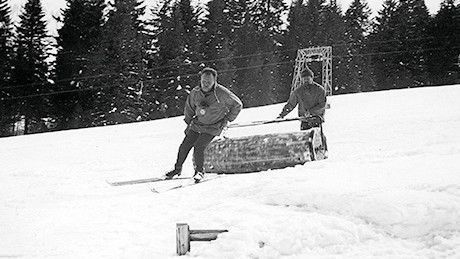 Ein Mann walzt die Skipiste manuell mit einer Handwalze